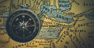 Brújula metálica con una aguja roja sobre un mapa antiguo amarillento con nombres de lugares