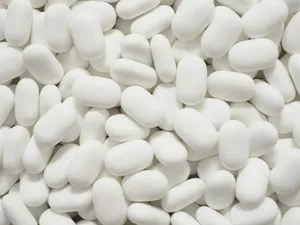 Comprimidos blancos ovalados amontonados, vistos de cerca
