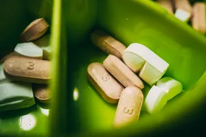 Comprimidos de varios tamaños y colores dentro de un recipiente de plástico verde