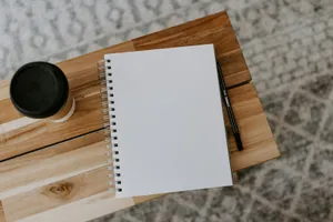 Cuaderno de espiral en blanco con un bolígrafo, sobre una tabla de madera