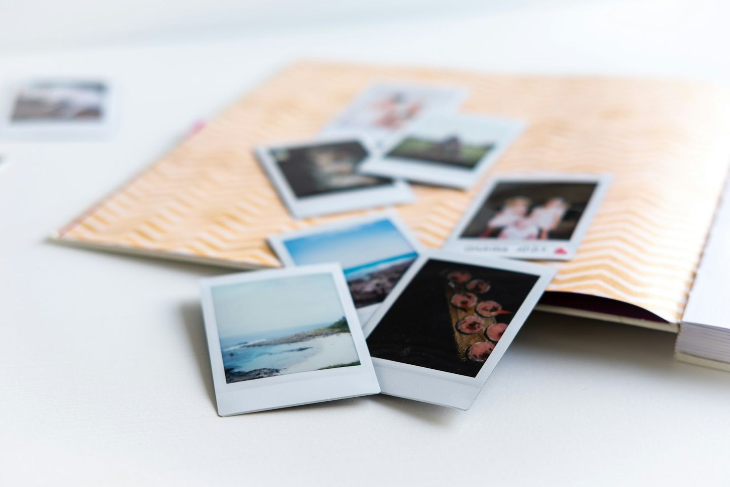 Fotos instantáneas esparcidas sobre una mesa blanca junto a un álbum abierto