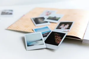 Fotos instantáneas esparcidas sobre una mesa blanca junto a un álbum abierto