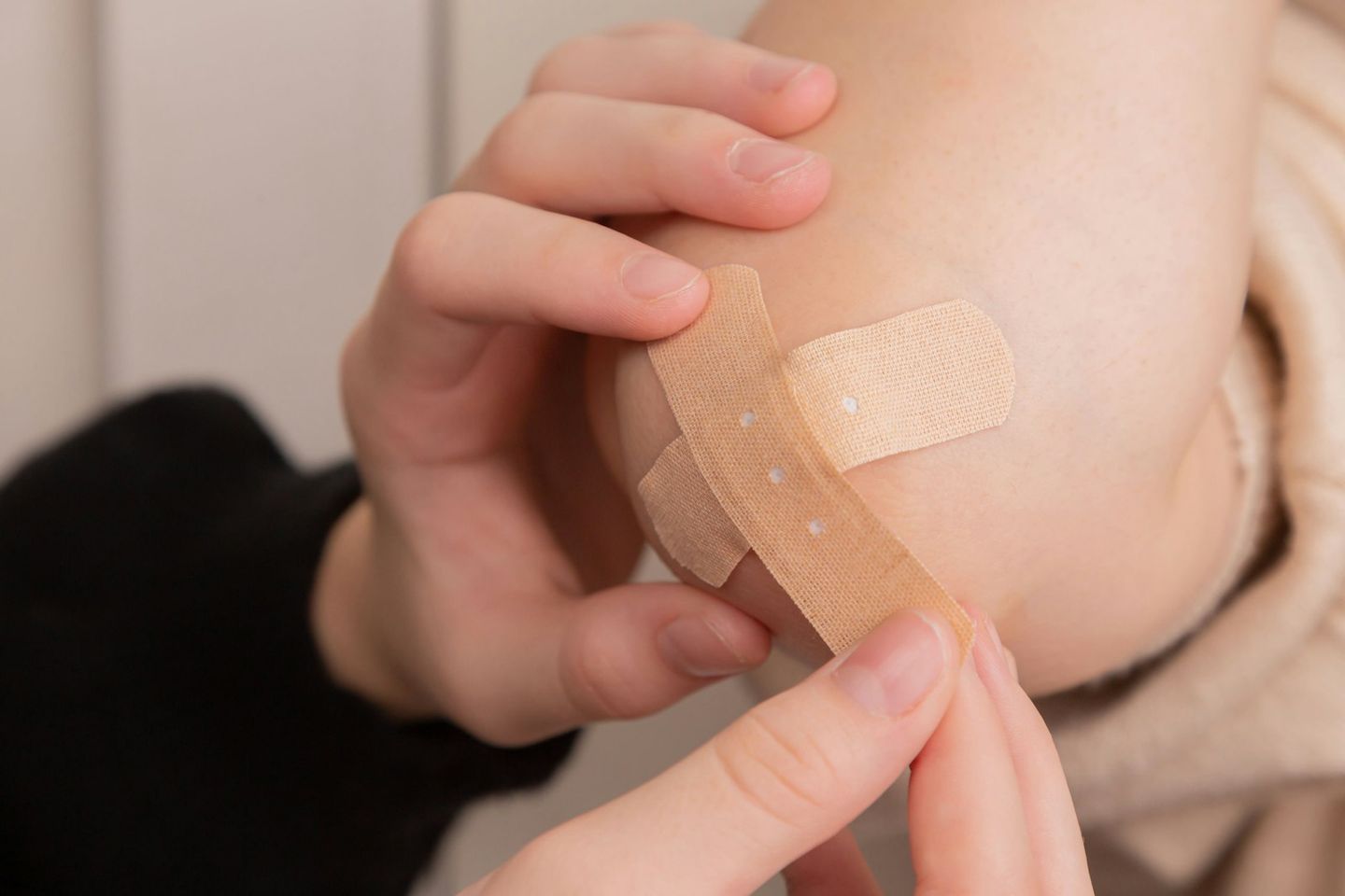 Manos colocando un apósito adhesivo sobre la piel de un brazo