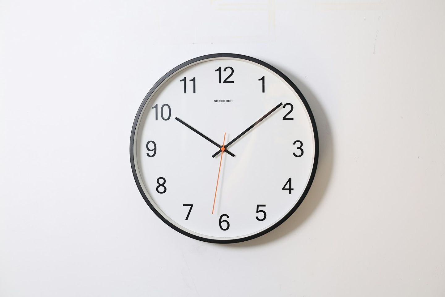 Reloj de pared con esfera blanca y números negros sobre una pared blanca