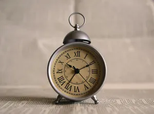 Reloj despertador antiguo con números romanos sobre unas páginas impresas