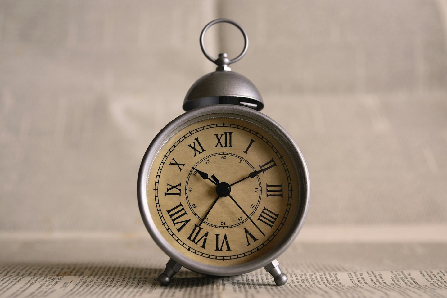 Reloj despertador antiguo con números romanos sobre unas páginas impresas