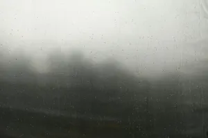 Ventana con gotas de lluvia y un paisaje neblinoso de fondo
